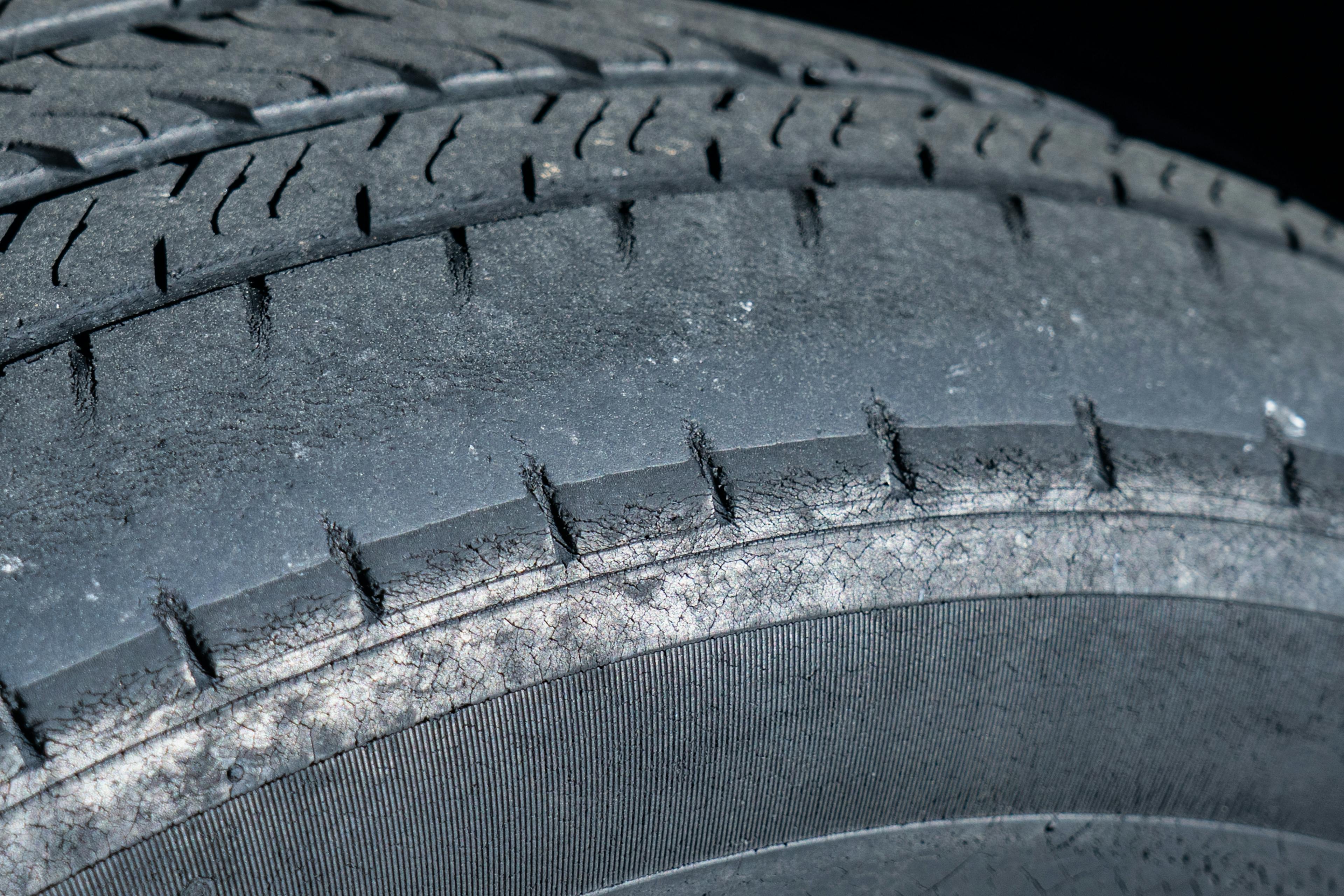 A picture of a car tyre with a worn outer edge caused by bad wheel alignment
