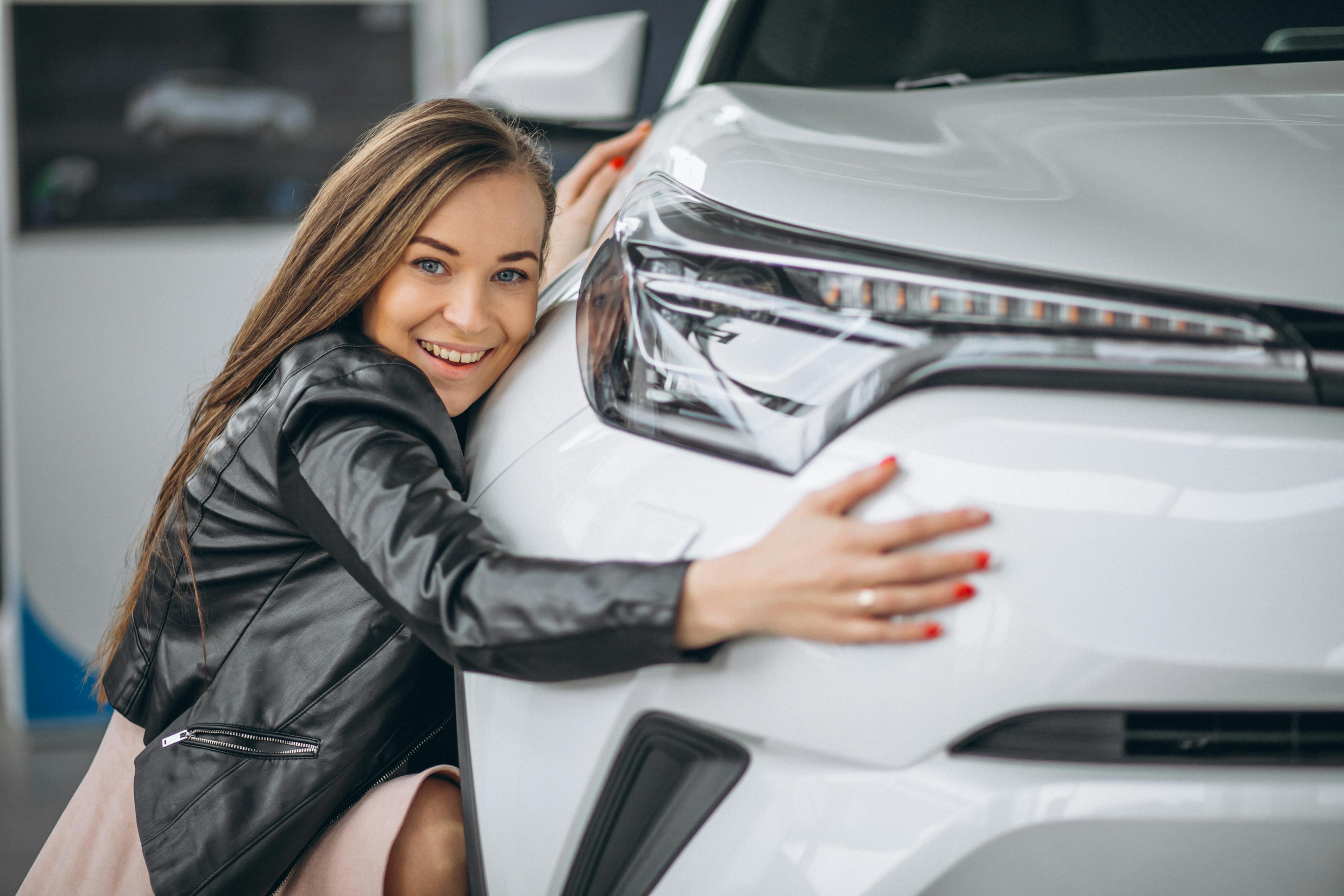 young woman in black leather jacket hugging new car