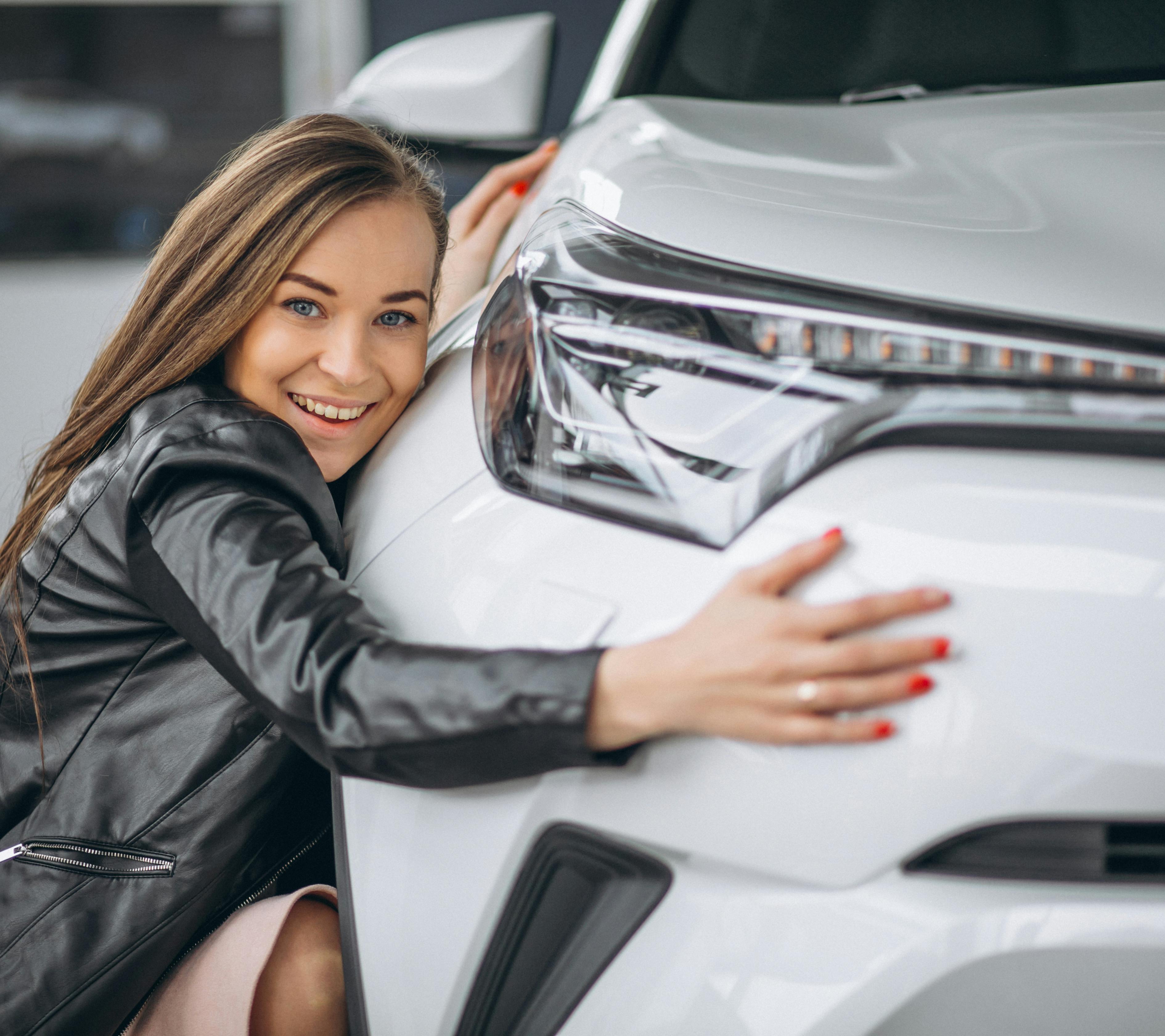 young woman in black leather jacket hugging new car