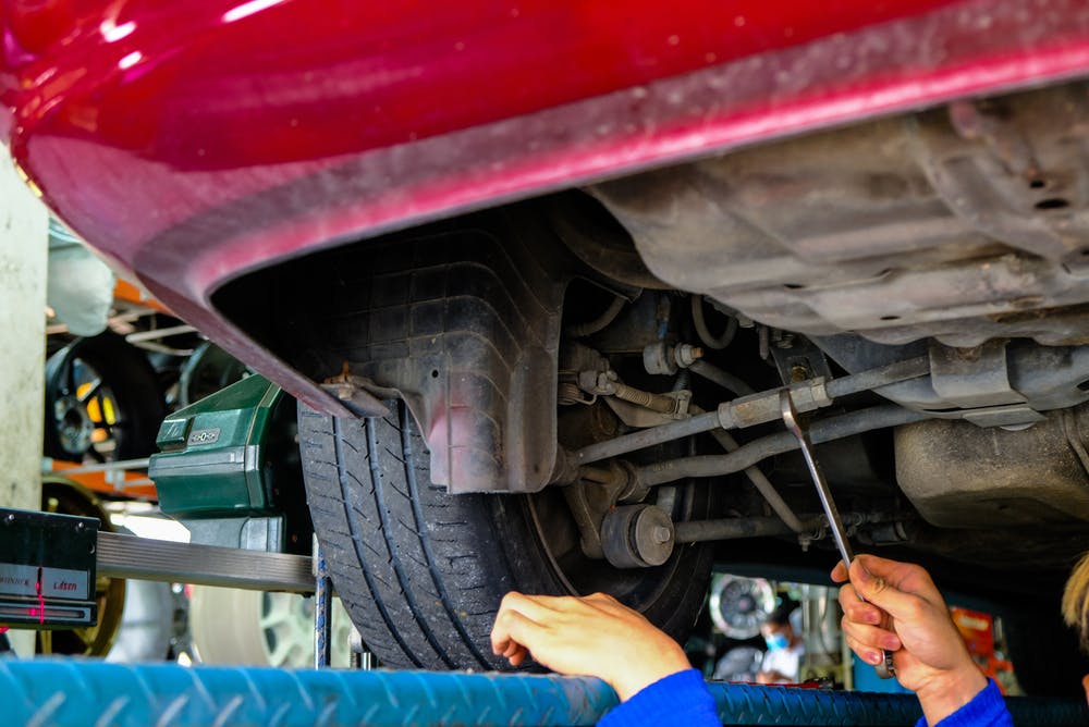 A mechanic making an adjustment with a spanner while carrying out a wheel alignment on a car