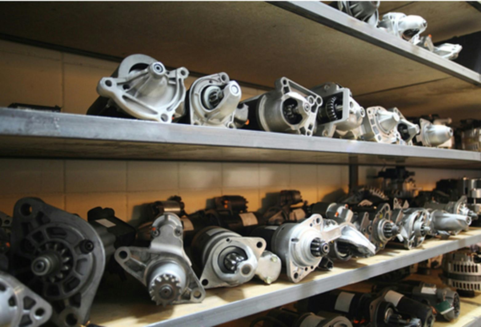 A collection of starter motors sitting on stock shelves
