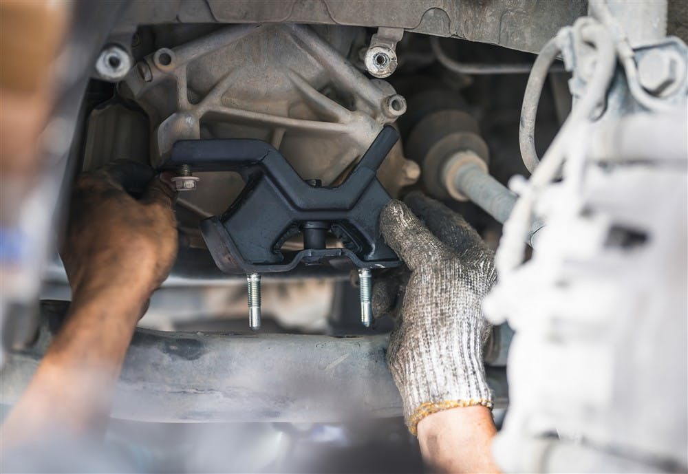 A mechanic replacing an engine mount