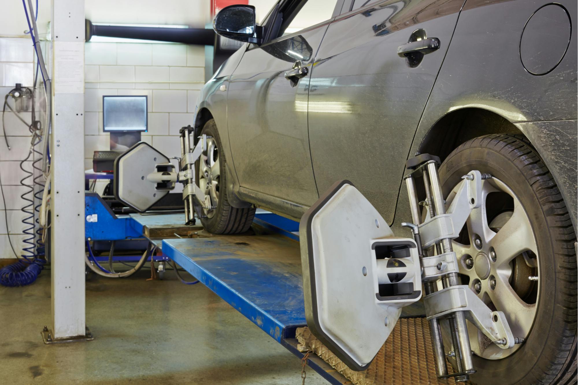 grey car having a wheel alignment at mechanic shop