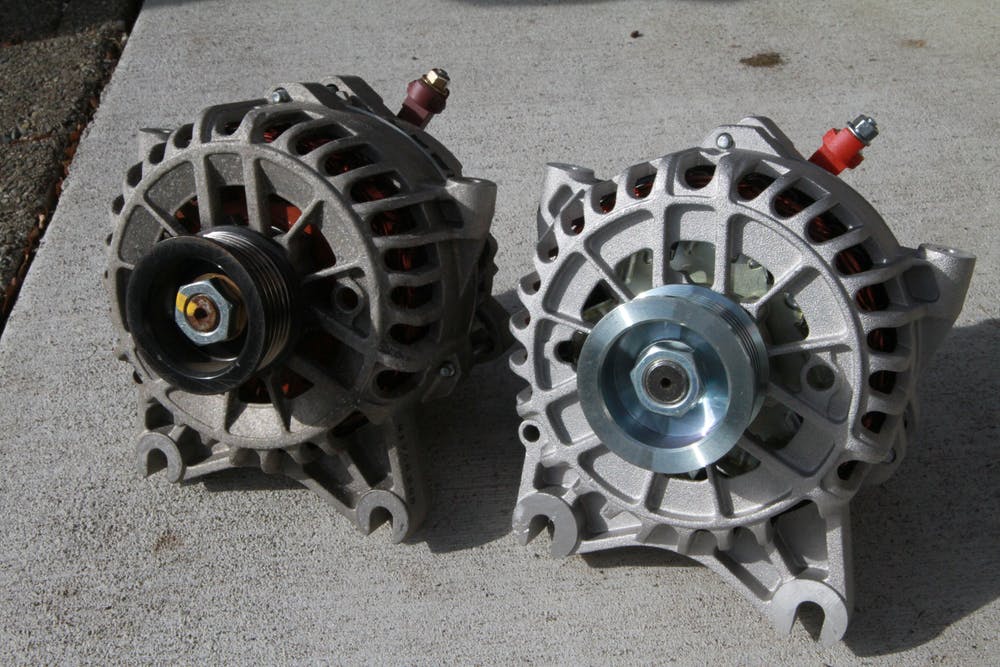 An old alternator and new alternator sitting side by side