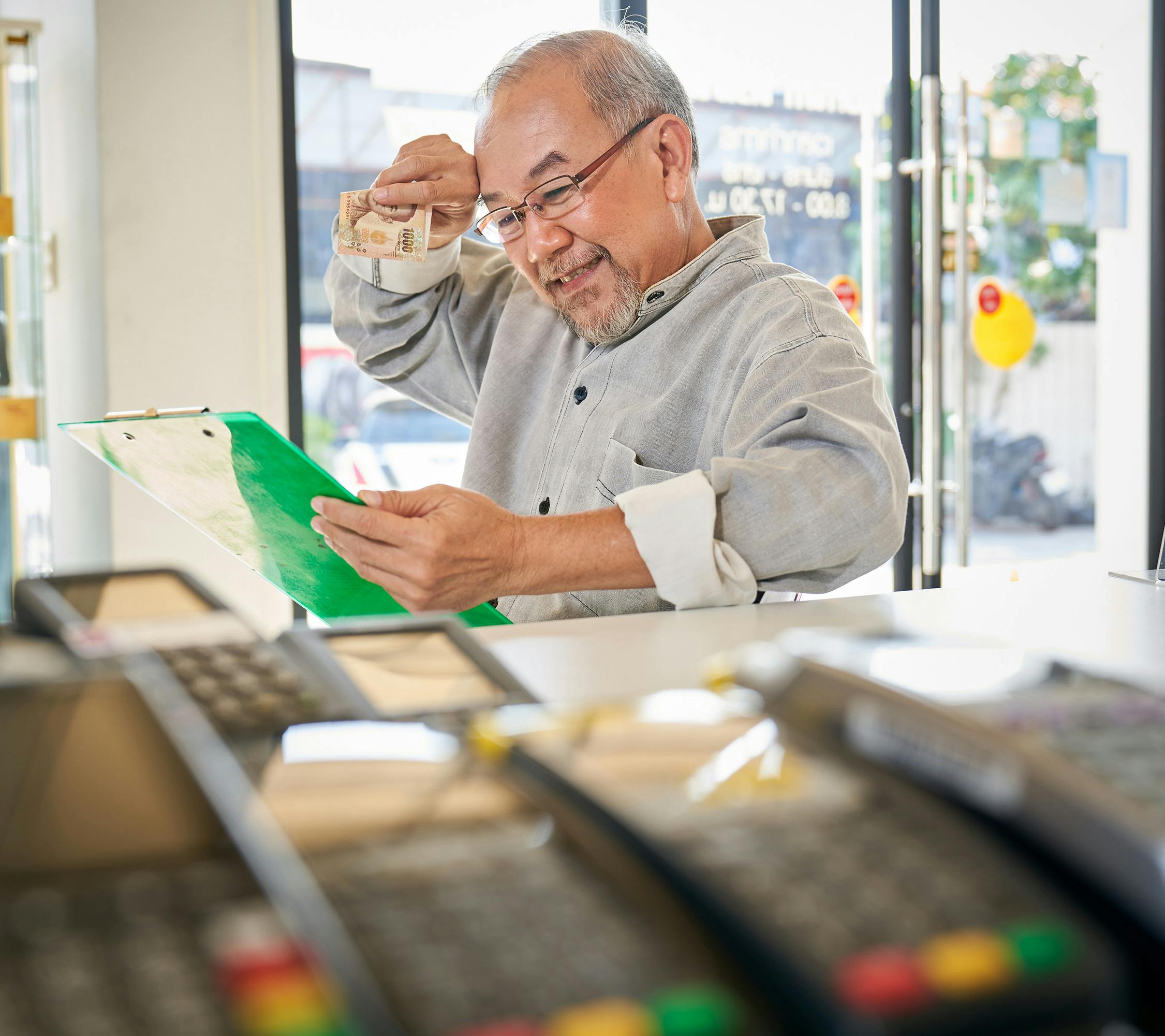 a man looking at a clipboard with eftpos machines in the foreground