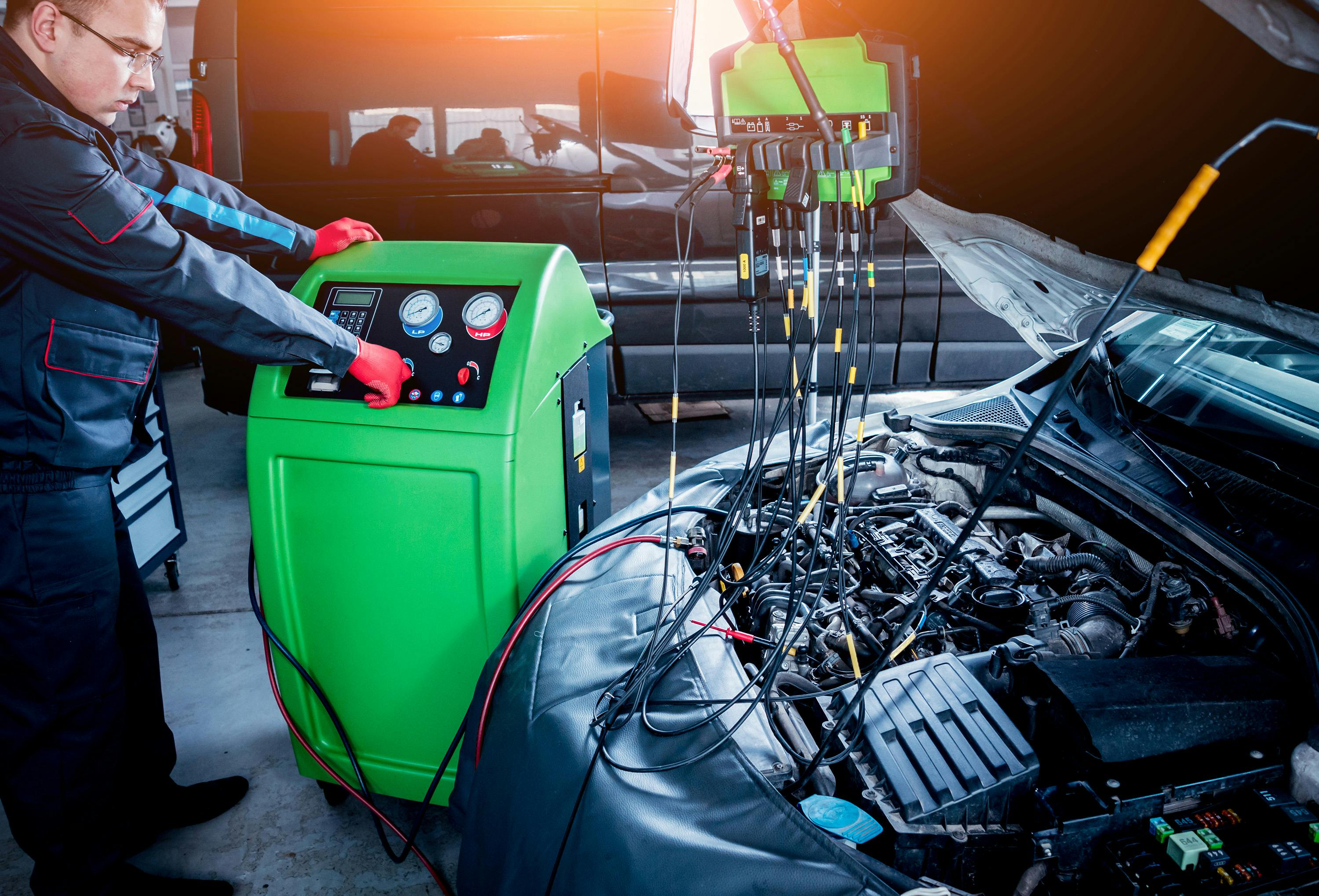 A mechanic using a refrigerant recovery machine on a car air conditioning system
