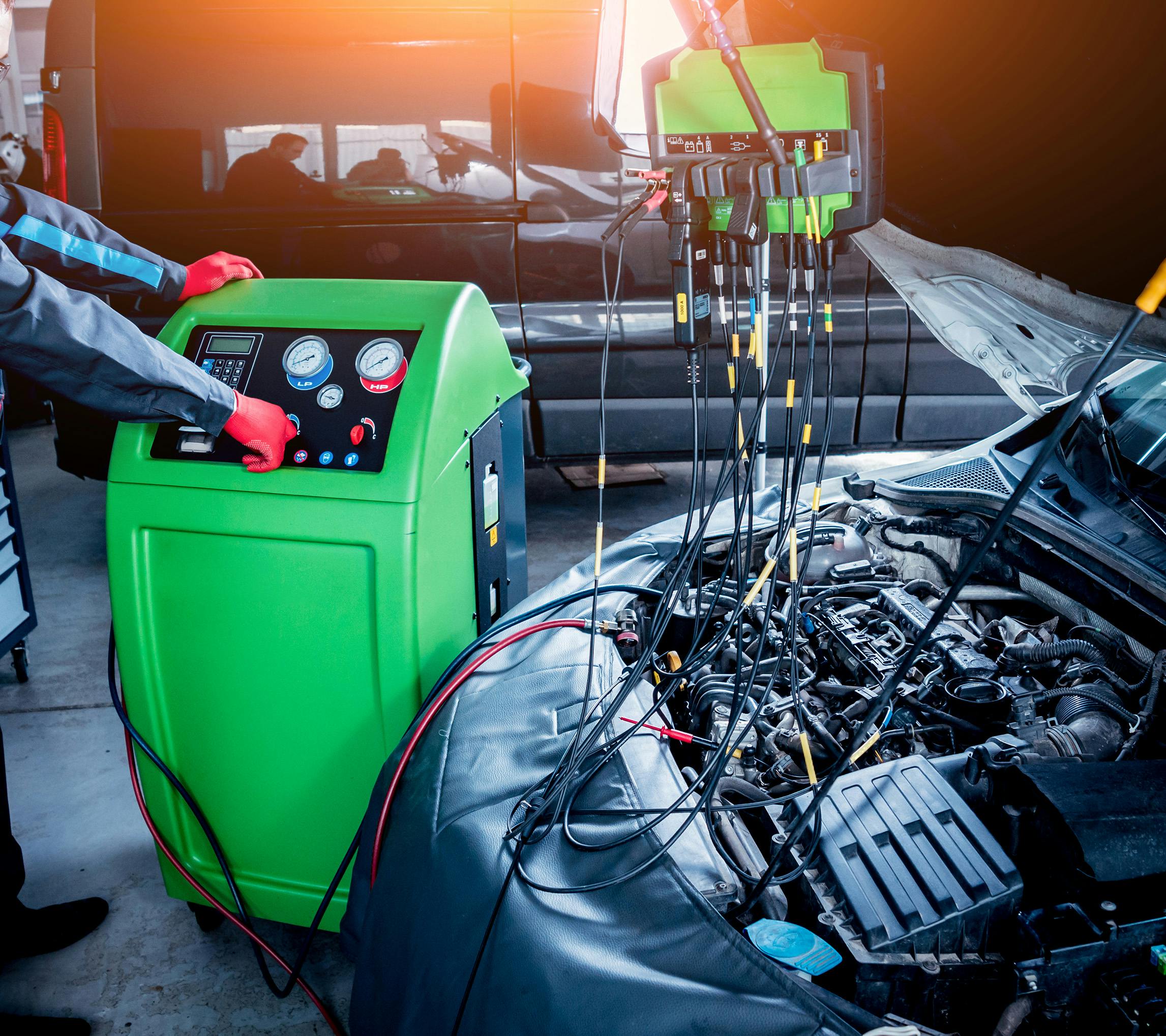 A mechanic using a refrigerant recovery machine on a car air conditioning system