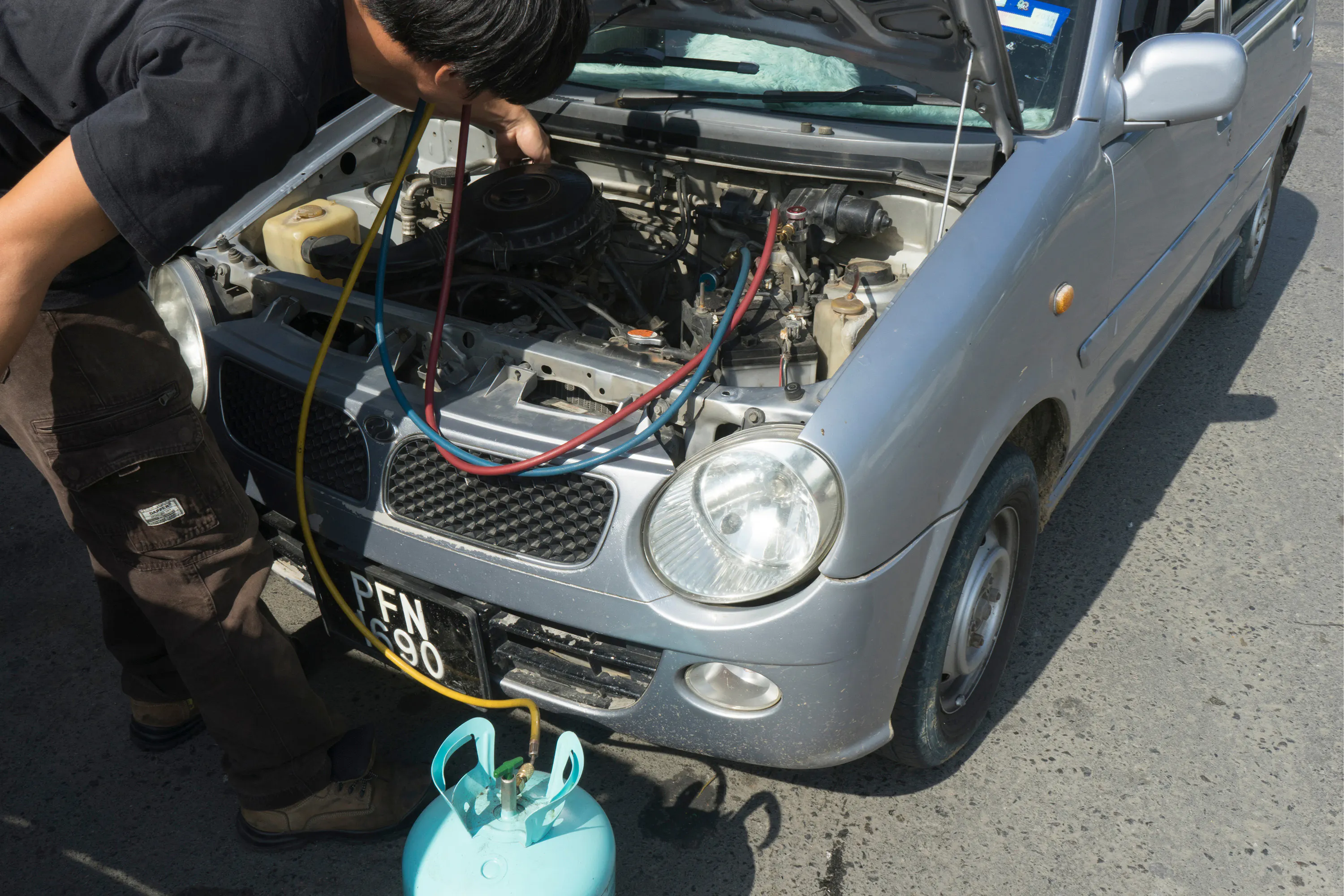 A mechanic carrying out an air conditioning regas on a car
