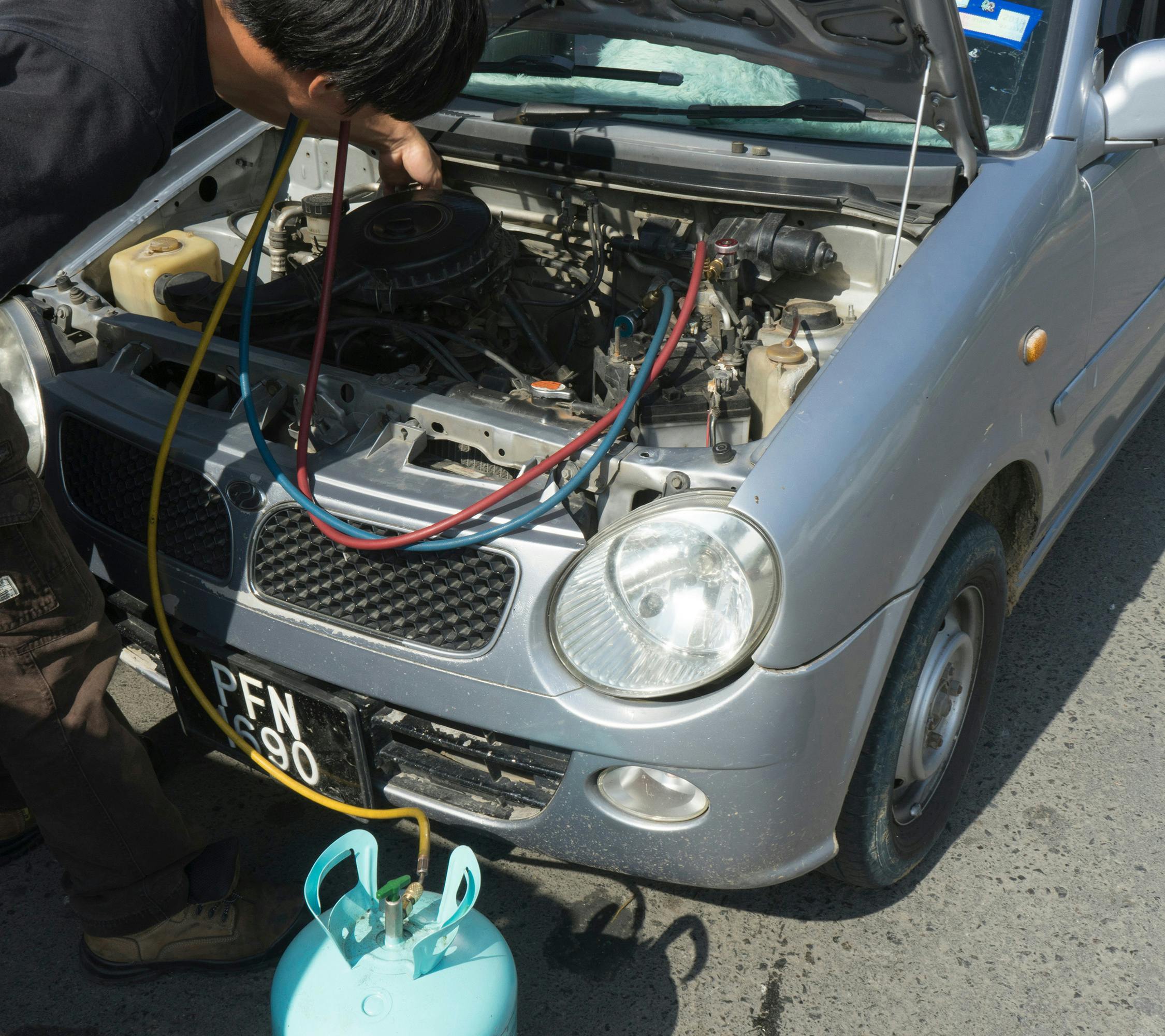 A mechanic carrying out an air conditioning regas on a car