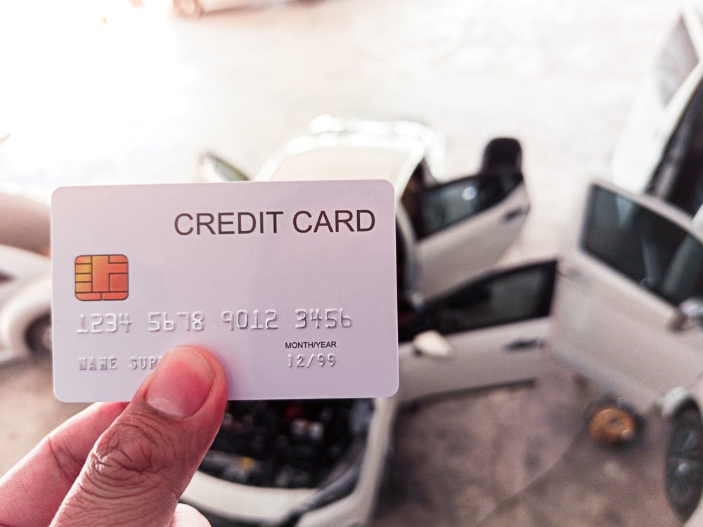 A person holding a credit card overlooking a car