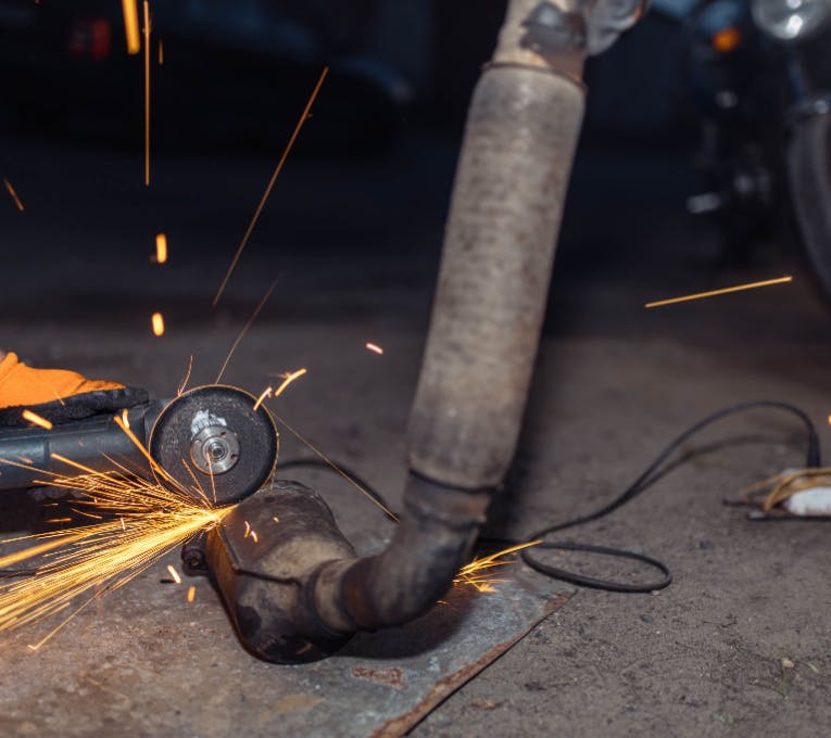 Technician cutting a DPF from an exhaust system with an angle grinder