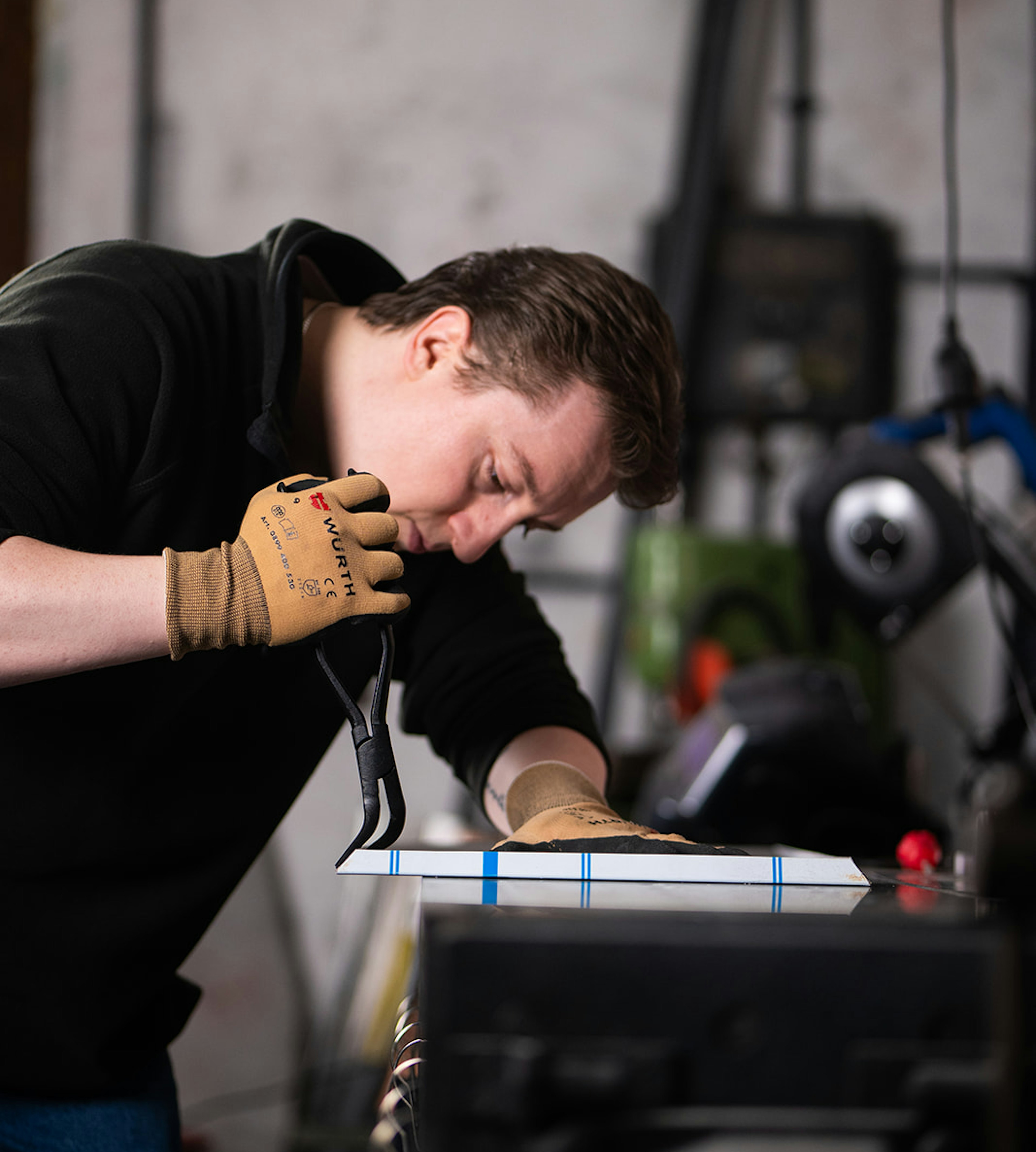 Mann bearbeitet Medaillenhalter aus Aluminium beim Zuschneiden in Werkstatt
