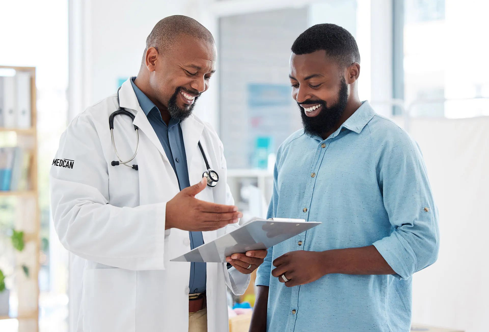 A professional man standing with his doctor, both smiling, reviewing chart
