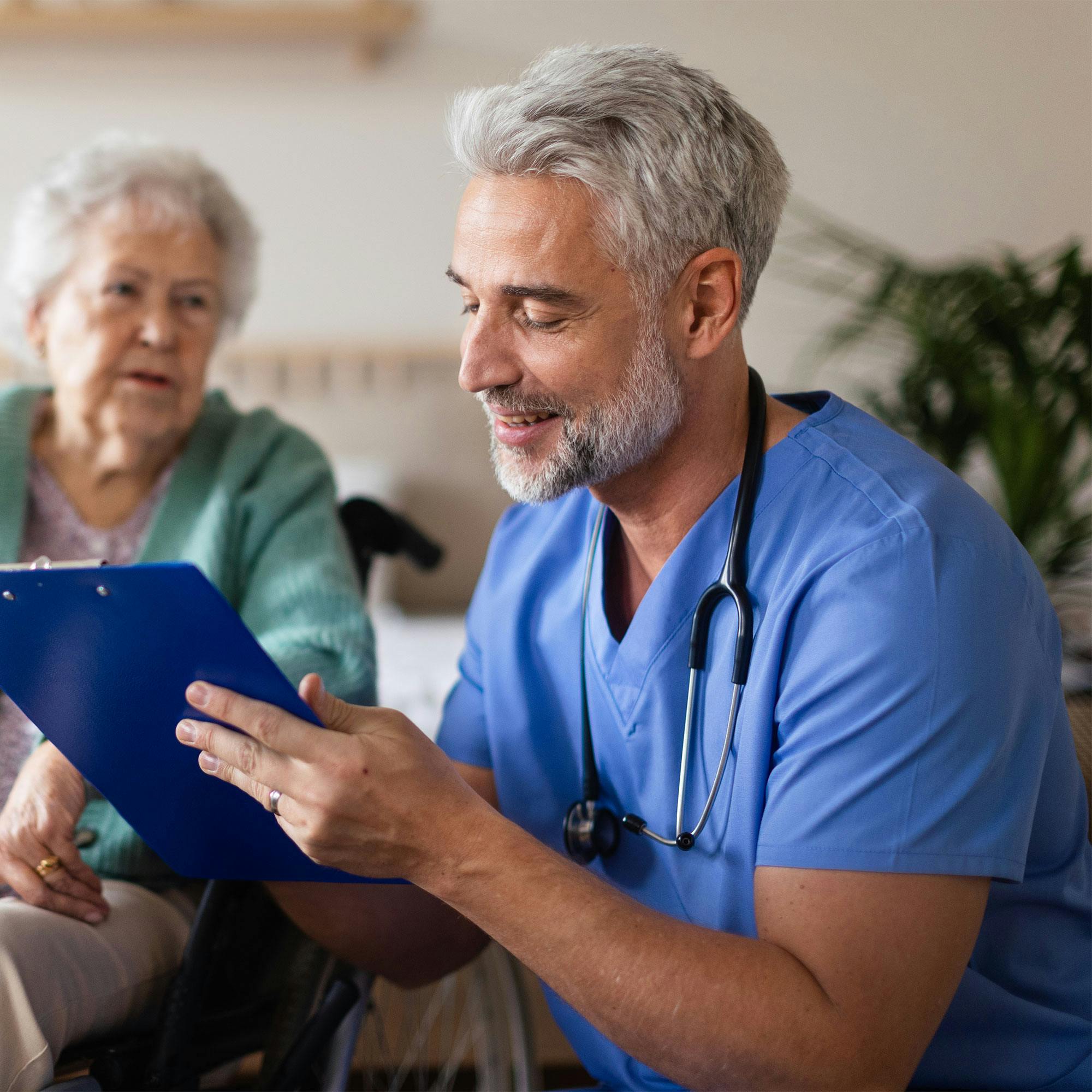 male nurse working on chart with elderly patient 