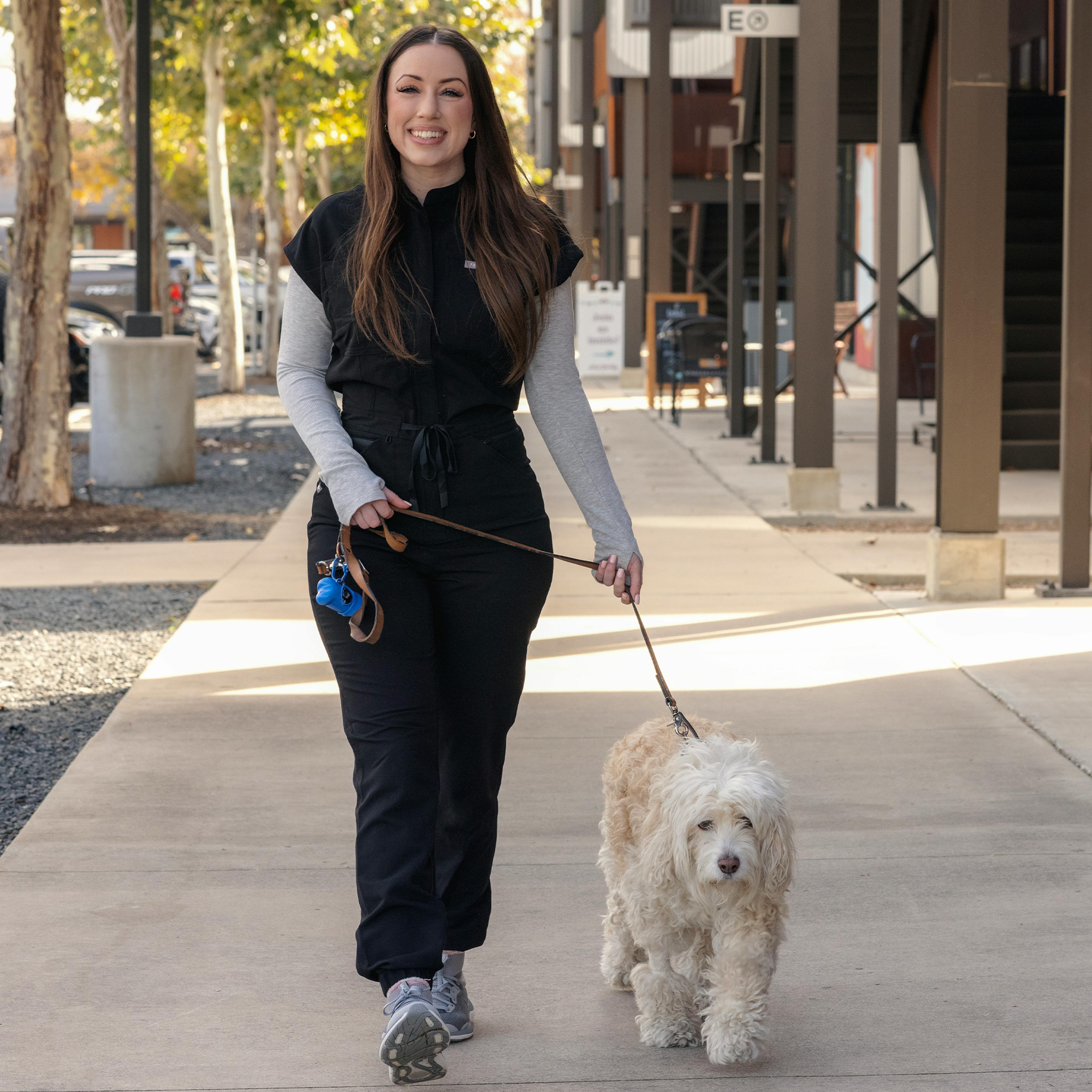 Nurse Kristen walking a dog in her scrubs