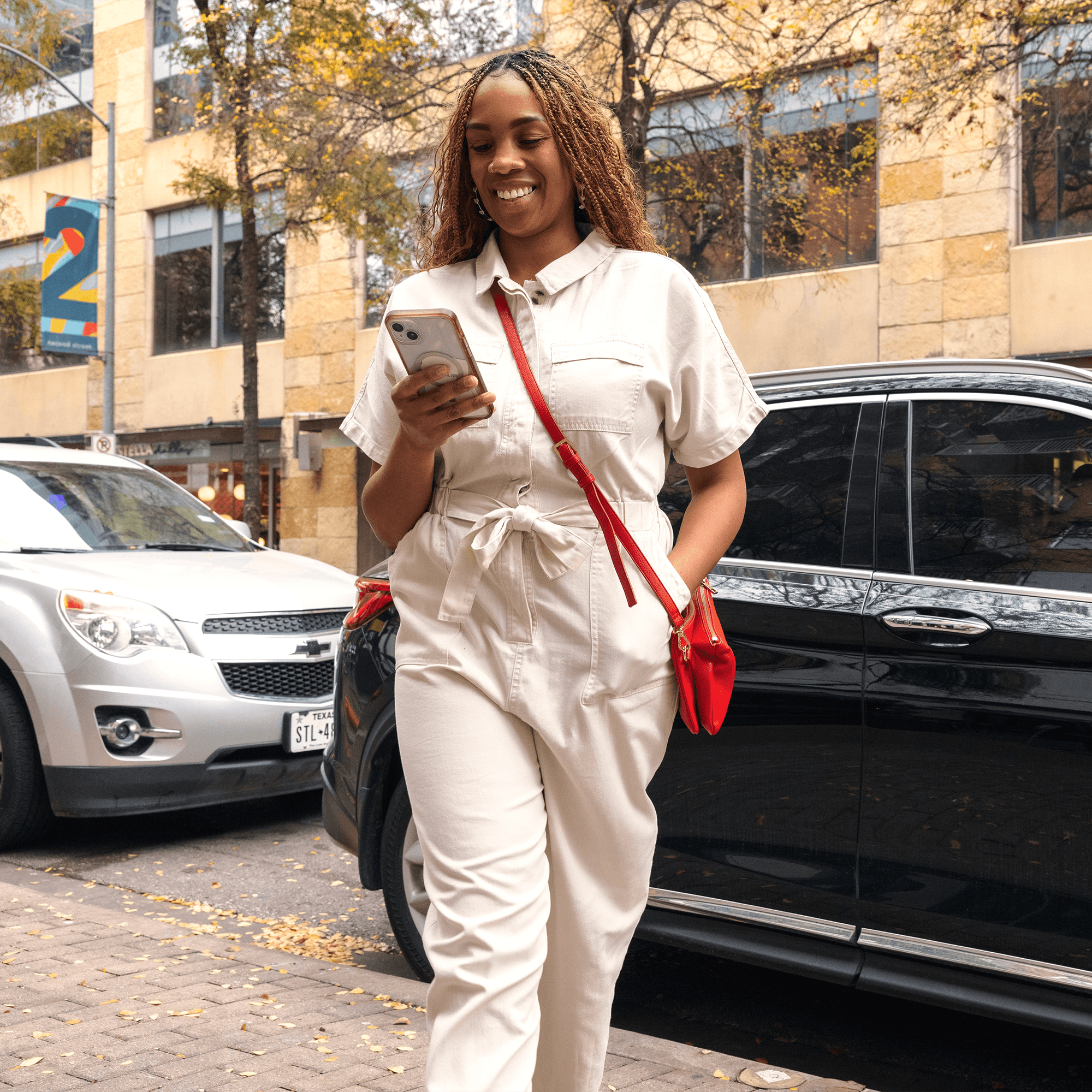 Woman walking away from car looking at her mobile device