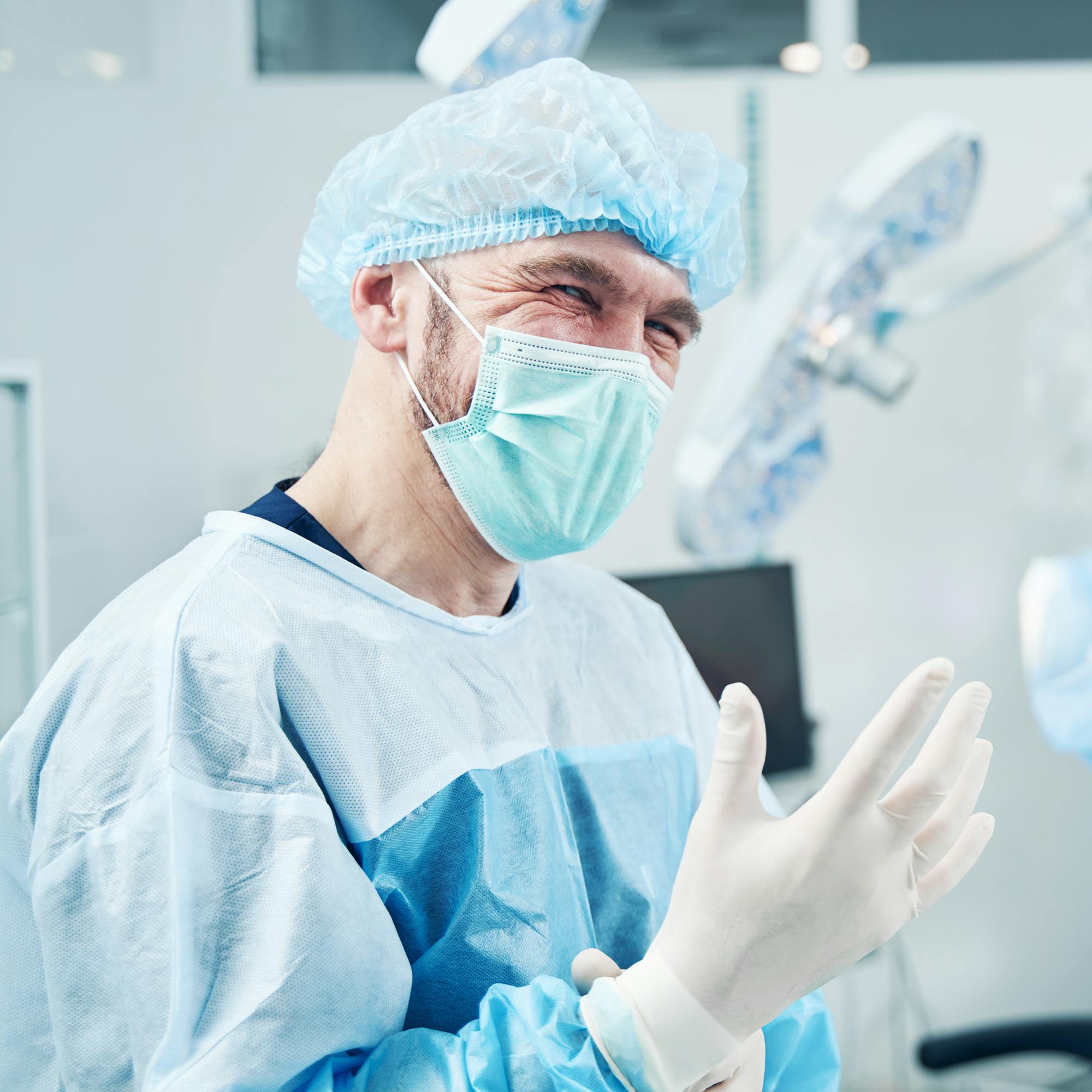 man in surgical outfit smiling in operating room