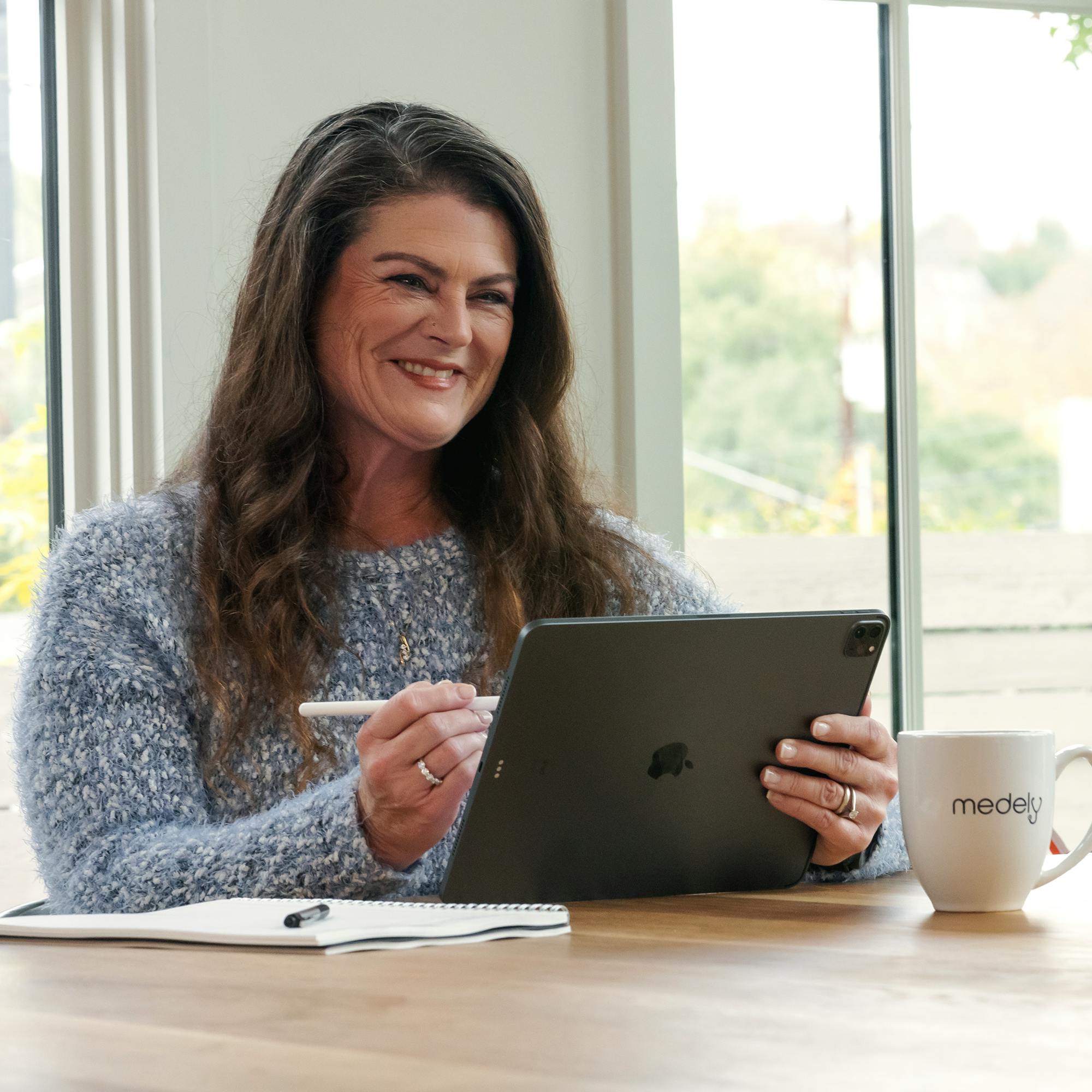 Image of RN administrator smiling while holding devices