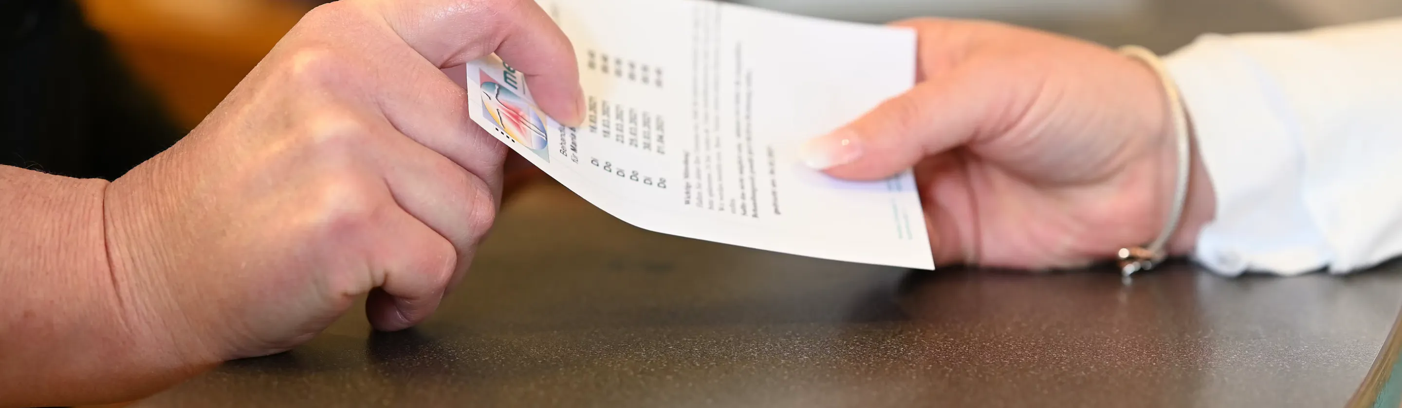 zwei Hände reichen sich ein Blatt Papier