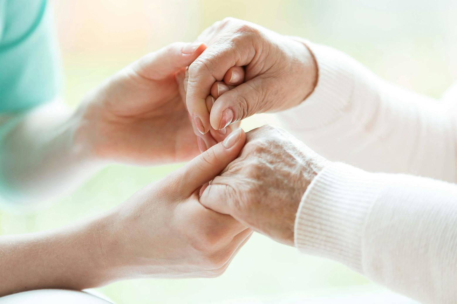 A photo of a nurse holding an elderly woman's hands, feeling hopeful about a diabetes drug for Alzheimer's treatment.