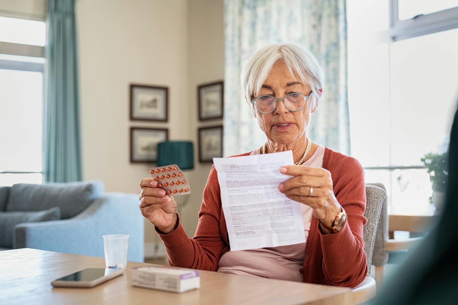 An elderly woman holding pack of Zantac pills representing the Zantac trial dates set in California.