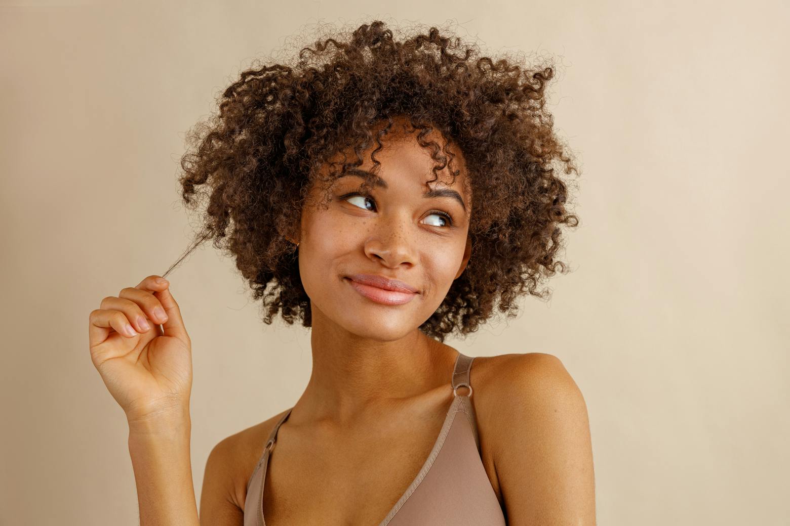 Image of a Black woman pulling a strand of her hair representing the hair relaxer lawsuits.