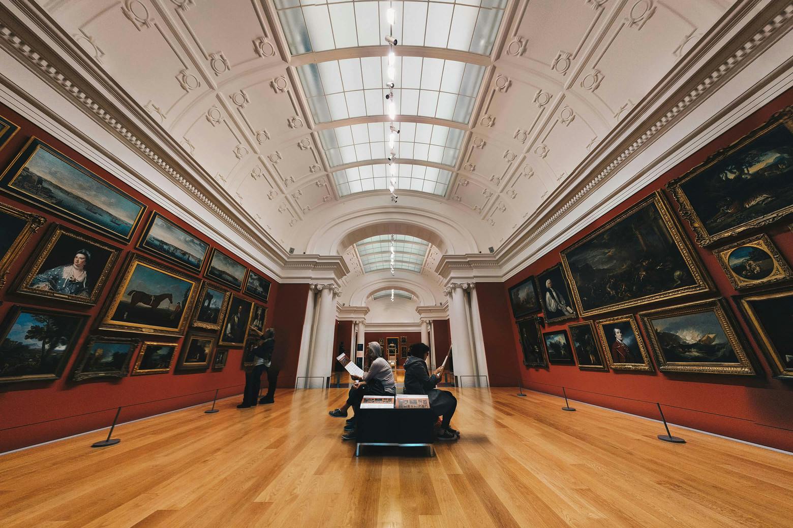 A photo of two people sitting in a museum, thinking about the Sackler family's part in the opioid crisis, which has caused museums to reject their donations.