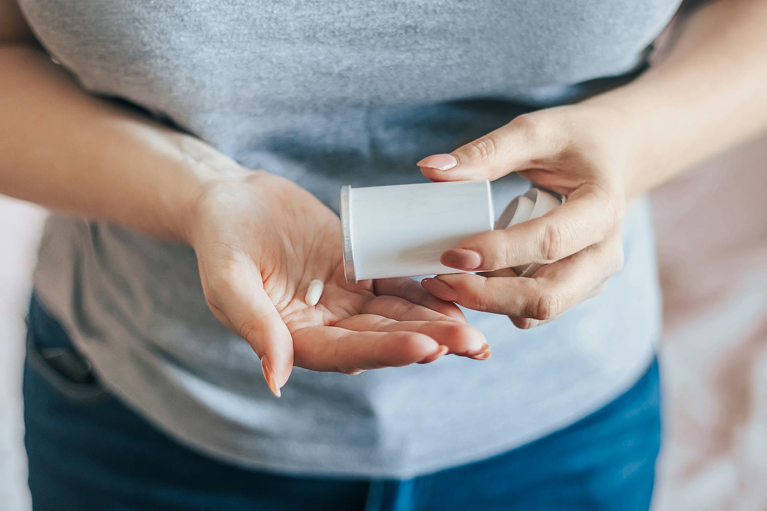 Woman holding a generic pill bottle representing Zantac makers pushing for MDL claims tossed.