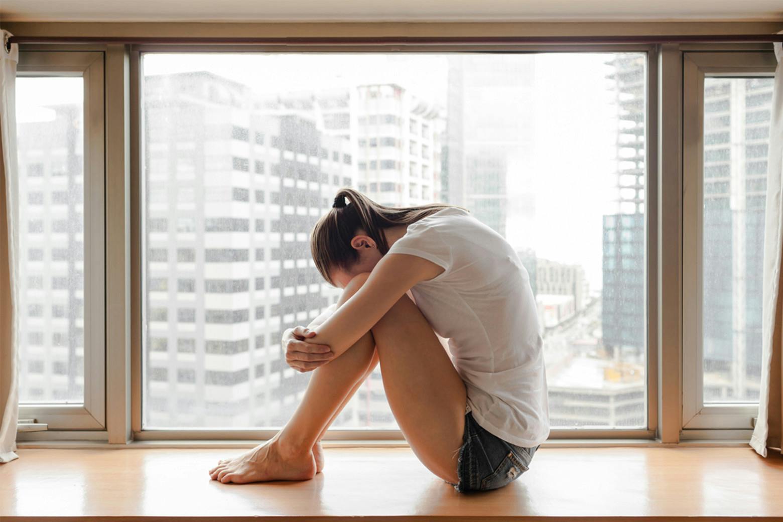 A photo of woman in pain huddled in the city for Chronicon New York to convey underrecognized Chronic Illness Defined by MedTruth.