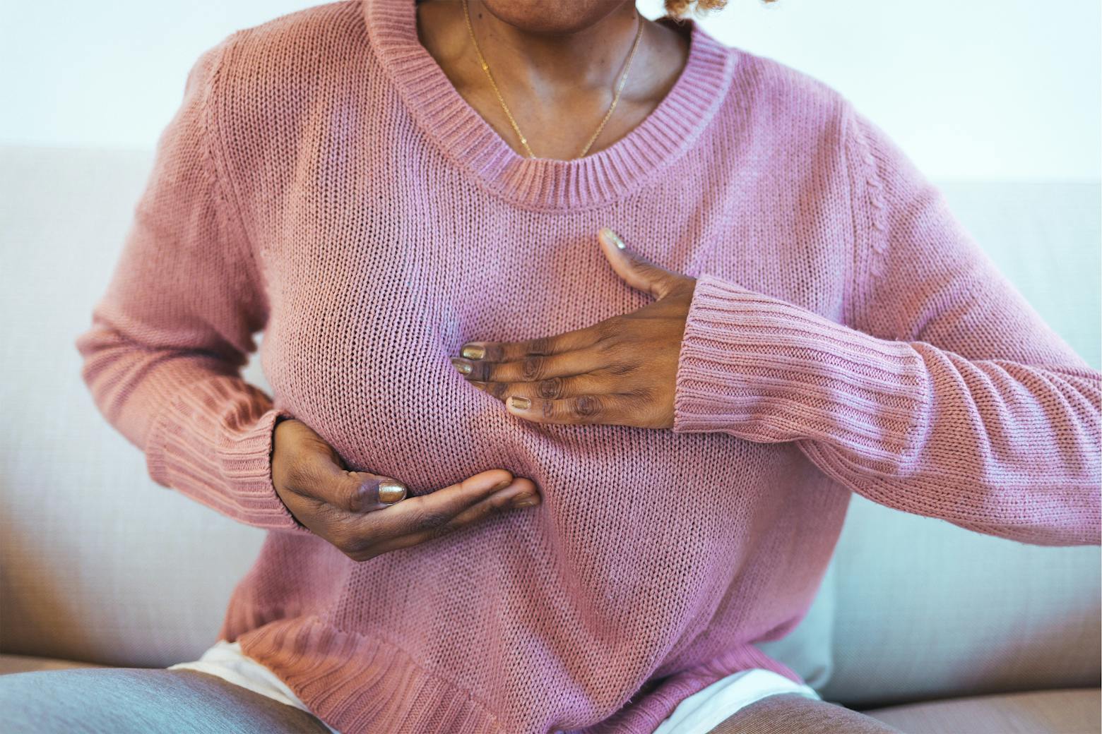 A woman feeling her breast experiencing breast pain representing the FDA's new breast implant study on risks of BIA-ALCL.