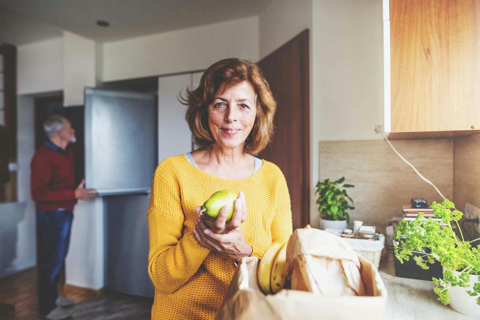 A photo of an older woman holding a piece of fruit, working with her husband to treat depression with diet.