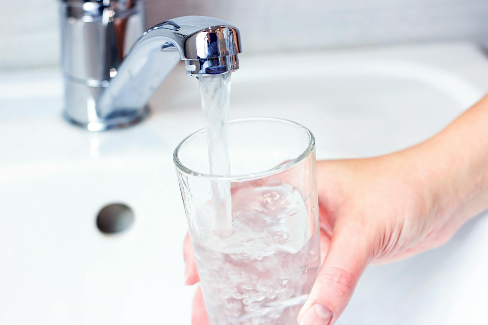 Person filling up a cup with tap water representing the PFAS drinking water class action lawsuit.
