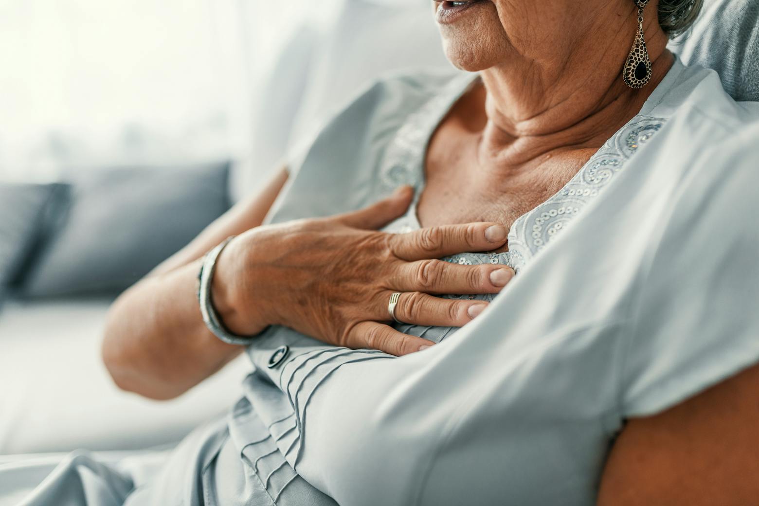 An elderly woman holding her chest with heartburn representing the Zantac cancer class action lawsuit dismissed.