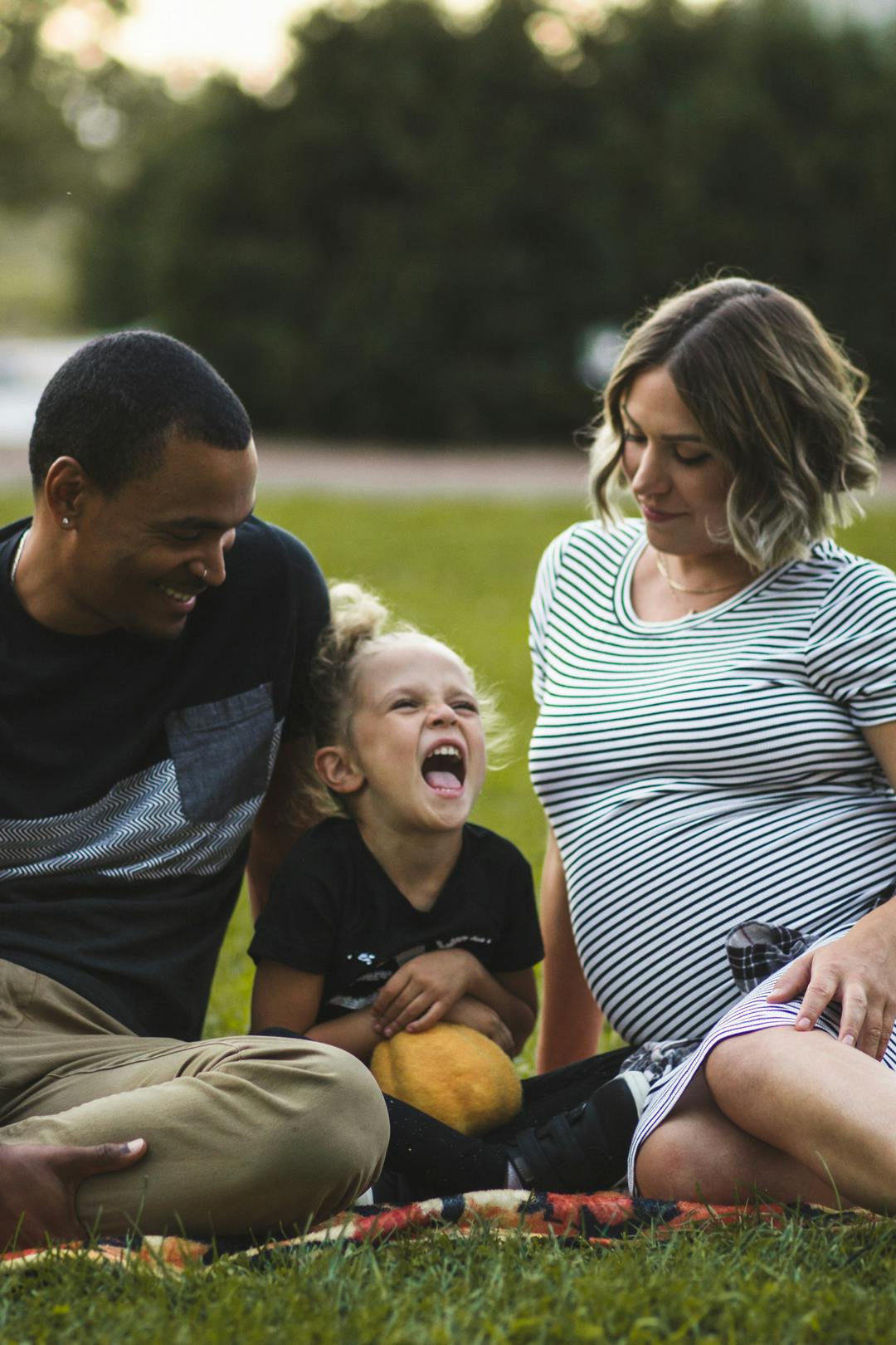 child screaming of laughter while parents smile at her happiness