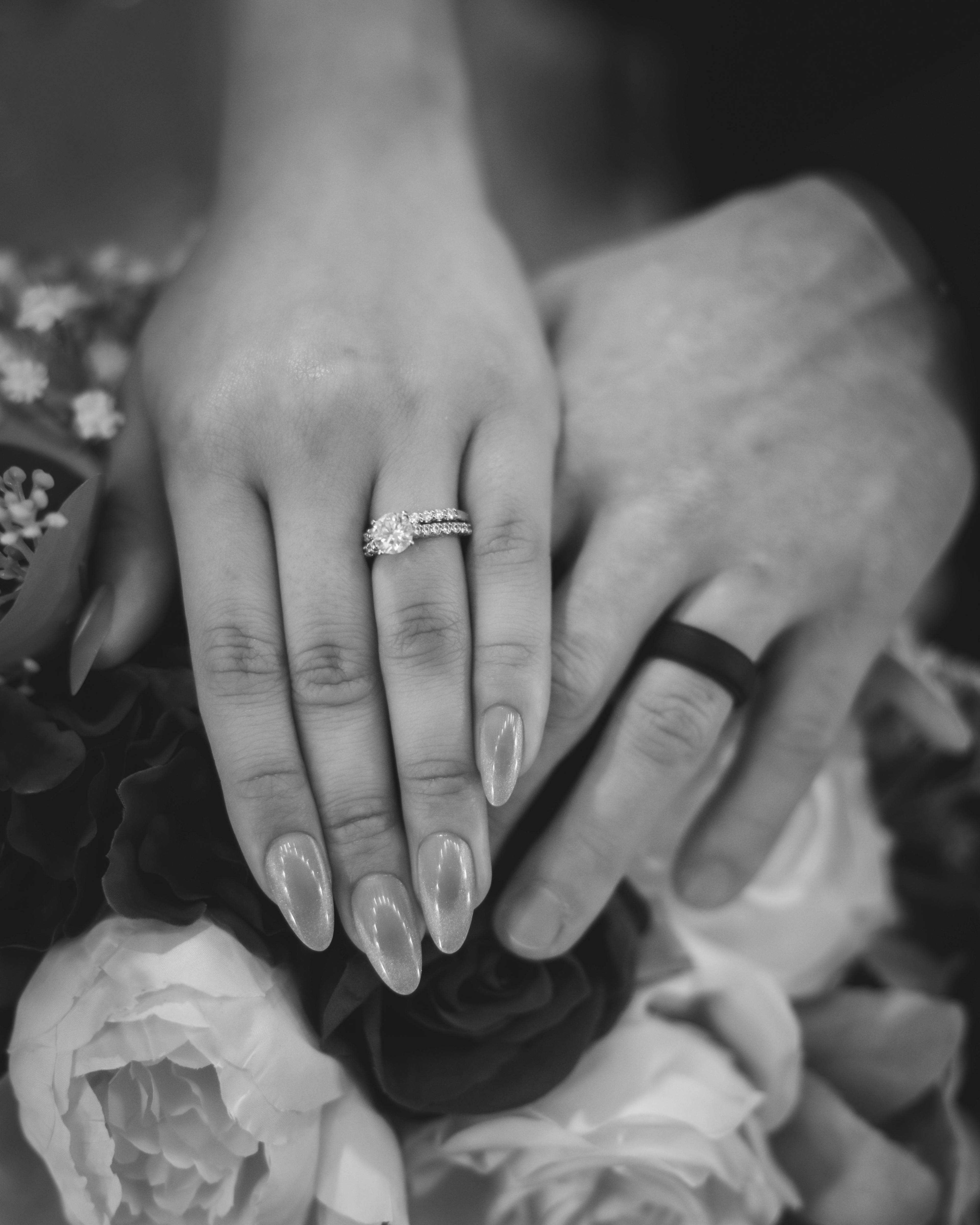 married couple resting their rings fingers on flowers