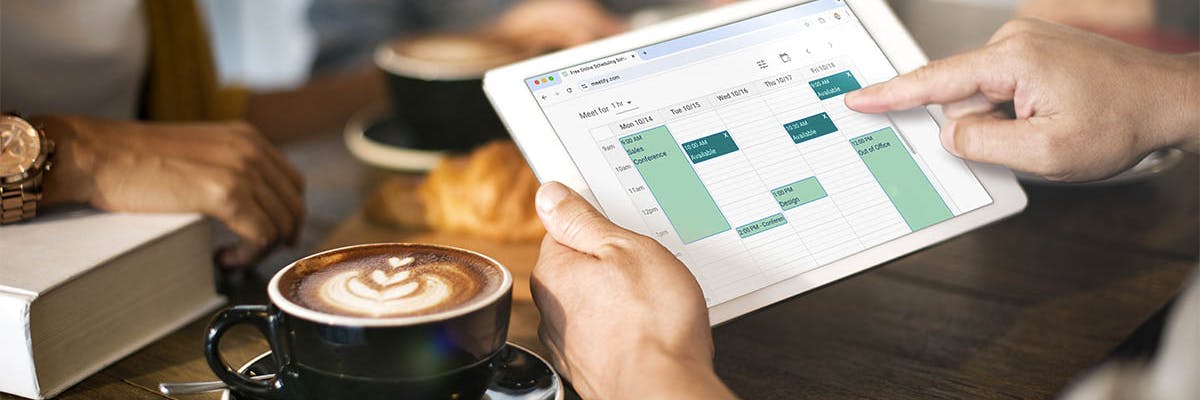 A man checks his Meetify calendar on a tablet in a coffee shop.