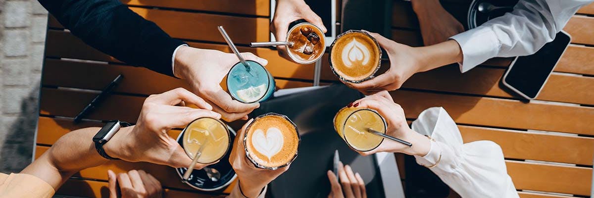 Coffee drinks held up in a circle at an in person business meeting