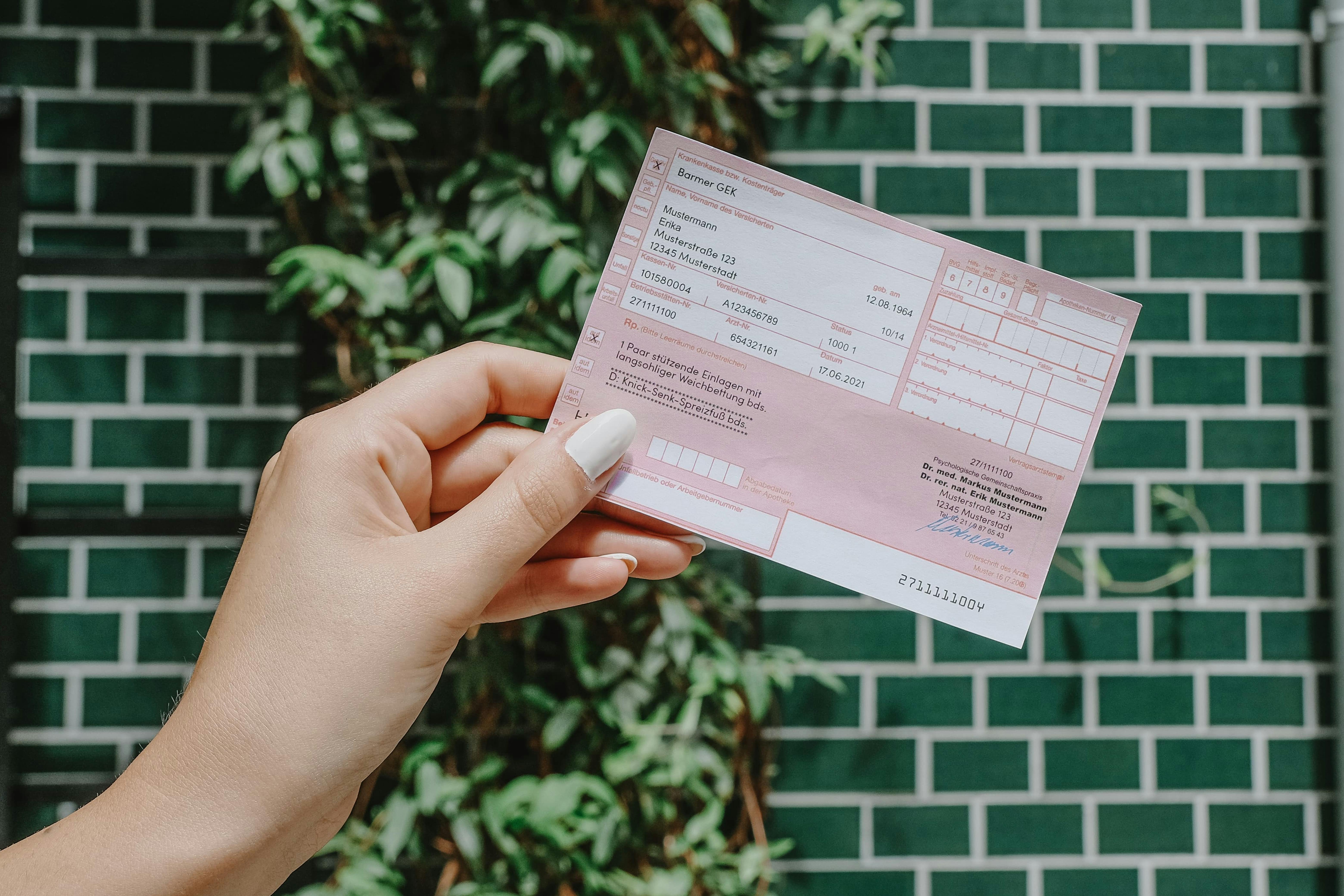 Frau hält Rezept in der Hand und steht vor eine grünen Wand.
