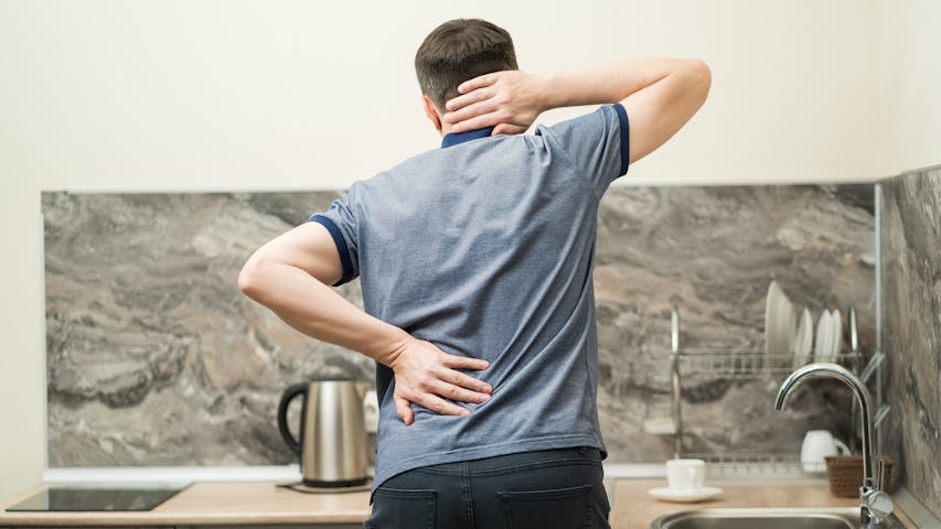 Mann greift sich an Nacken und Hüfte