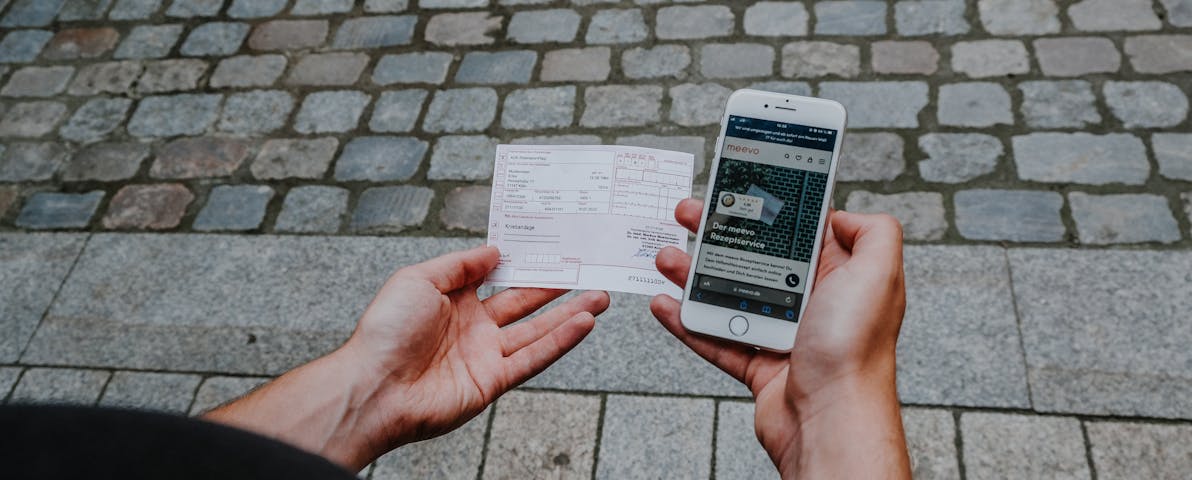 Mann hält Handy und Rezept in der Hand.