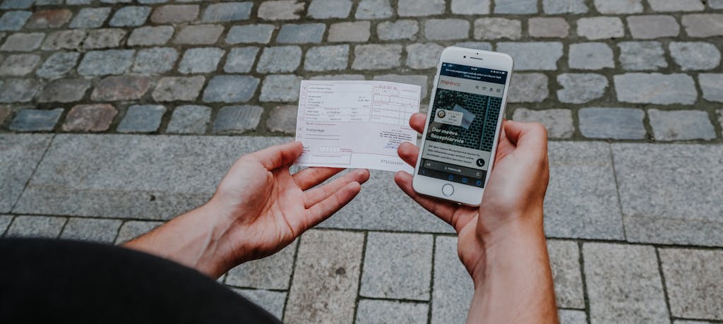 Mann hält Handy und Rezept in der Hand.