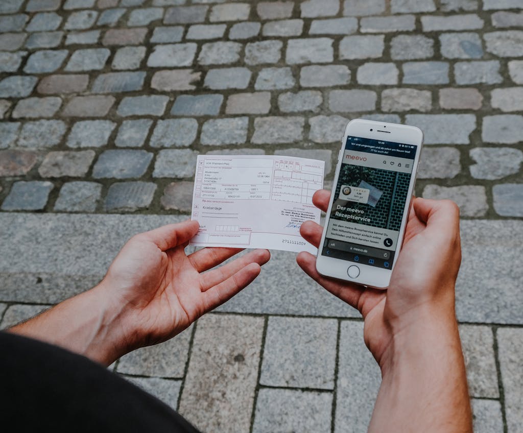 Mann hält Handy und Rezept in der Hand.