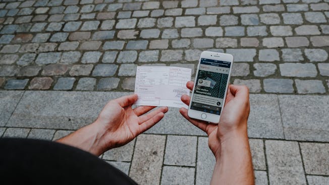 Mann hält Handy und Rezept in der Hand.