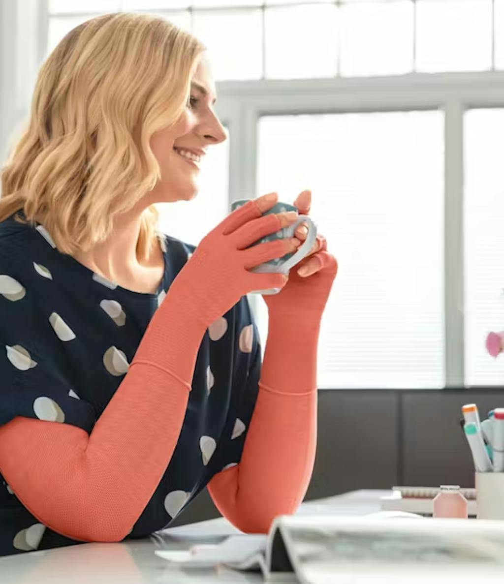 Frau mit Armkompression und Kaffee in der Hand