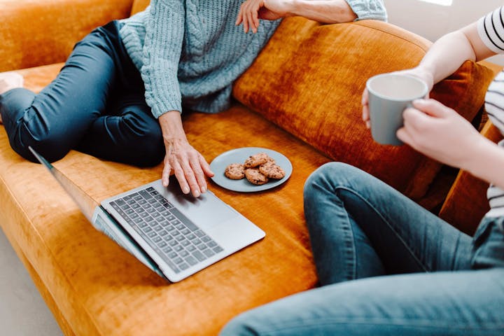 Zwei Personen sitzen auf dem Sofa am Laptop.