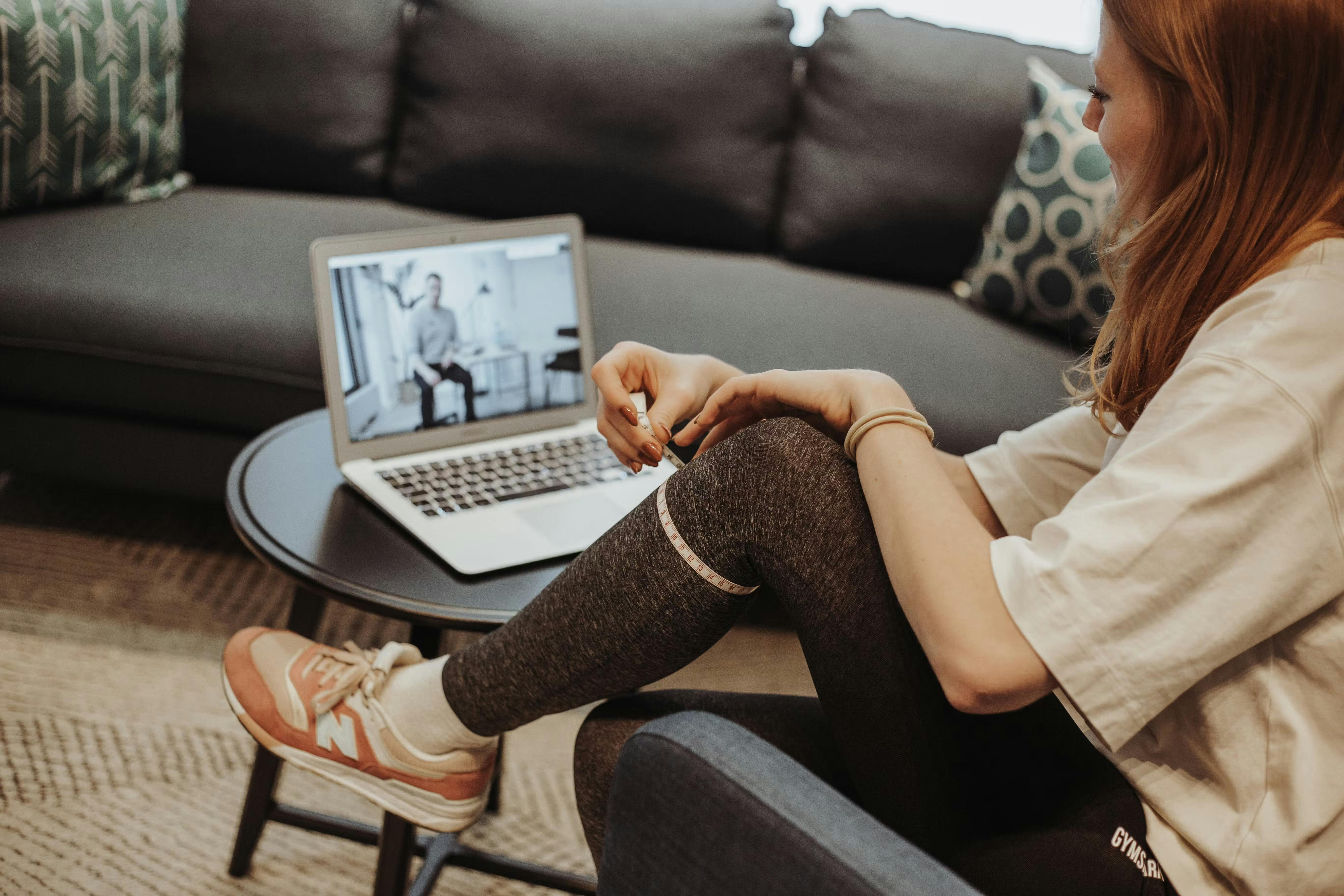 Frau vermisst ihr Knie, während Sie online eine Videoberatung über den Laptop empfängt