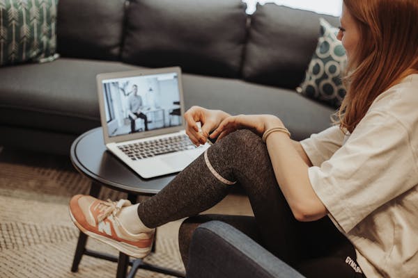 Frau vermisst ihr Knie, während Sie online eine Videoberatung über den Laptop empfängt