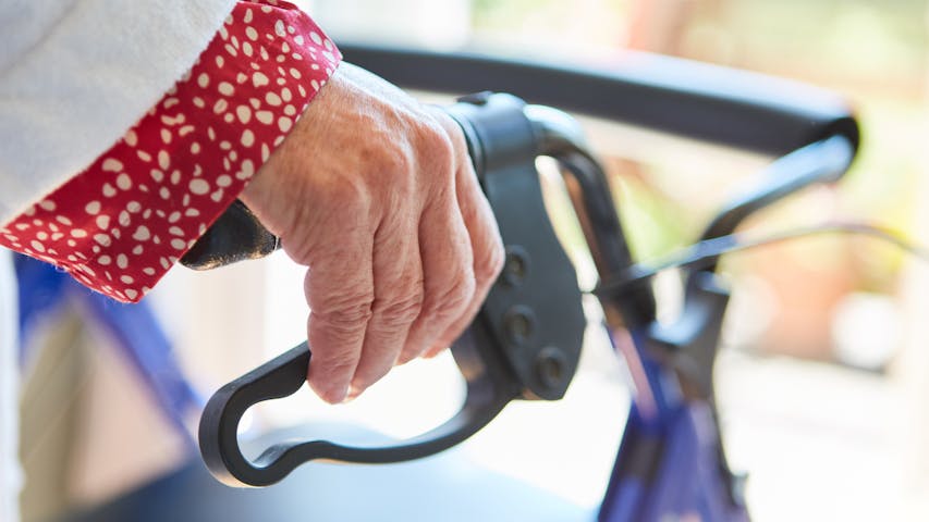 Frau hält Griff von Rollator
