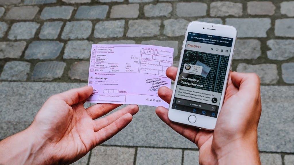 Mann hält Rezept und Handy in der Hand.