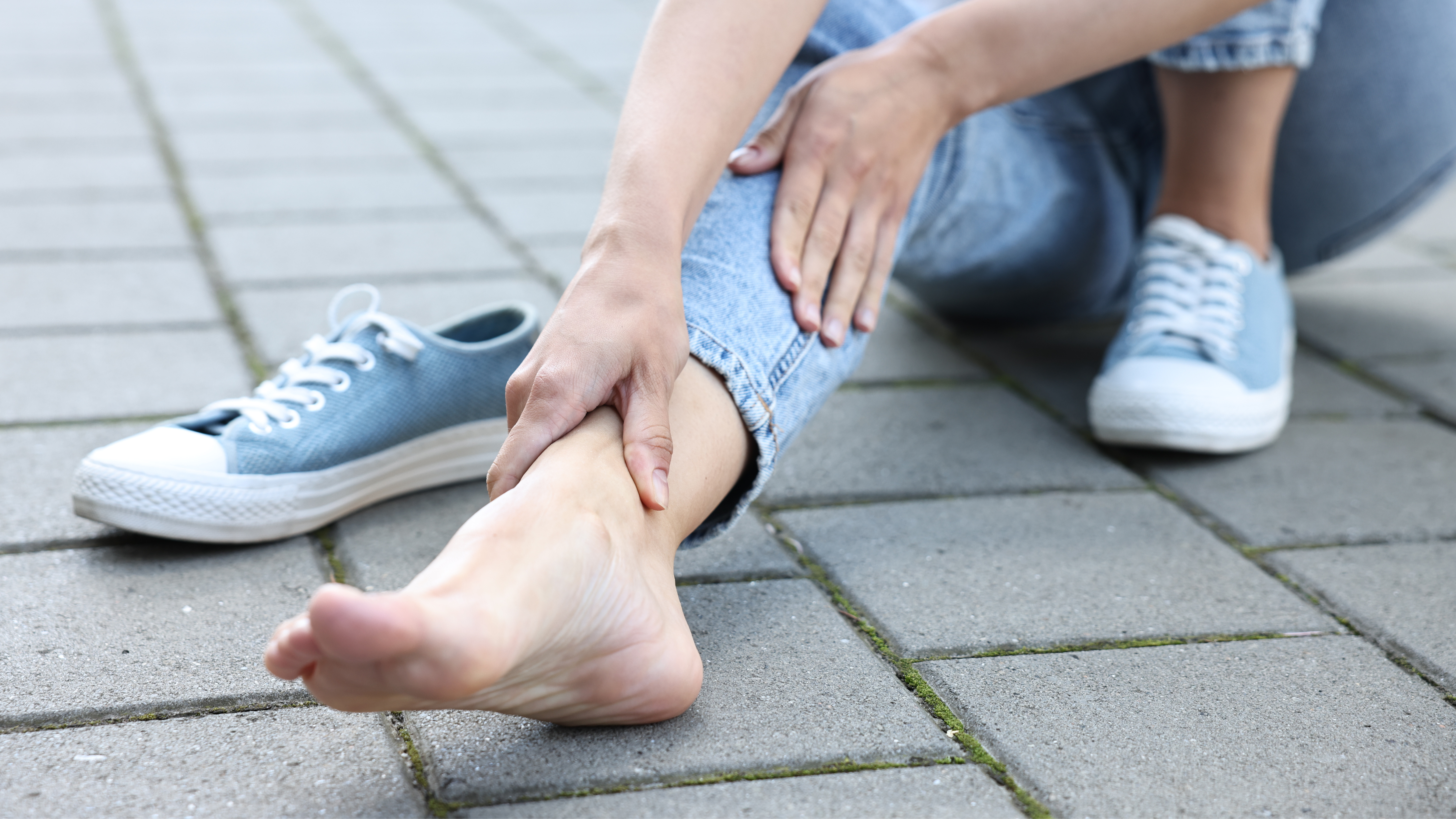 Frau greift sich an den Fußknöchel
